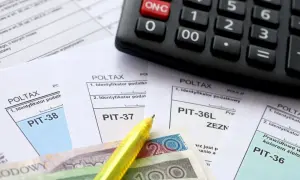 Kalkulator, formularze PIT, pieniądze i żółty długopis na tle dokumentów podatkowych.