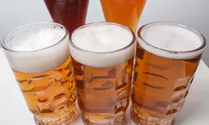 Tre bicchieri di birra dorata con schiuma bianca, uno più scuro e uno arancione sullo sfondo. Un invito a scoprire la differenza tra pils e lager.