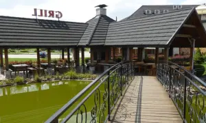 Drewniany mostek nad zielonym stawem prowadzi do altany z grillem. Wiele atrakcji czeka w Trzciance!