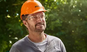 Hombre con casco naranja y gafas de seguridad, listo para usar su epi desbrozadora.