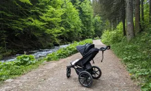 Wózek dziecięcy na leśnej ścieżce. Idealne zakopane szlaki dla dzieci z wózkiem, obok szumiącego potoku.