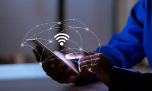 Dłoń dotyka ekranu smartfona, nad którym unosi się grafika symbolizująca sieć i sygnał Wi-Fi. To połączenie z apn plus.