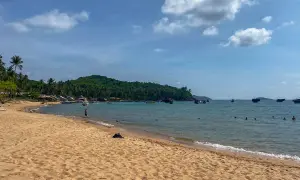 Piękna plaża z palmami, łodzie na turkusowym morzu i zielona wyspa. To idealne miejsce na odkrywanie Wietnamu na własną rękę.