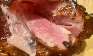 Gros plan sur des kakos de porc juteux et caramélisés, la chair rose tendre contrastant avec la peau croustillante.