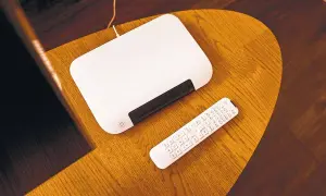 Biały router i pilot na drewnianym stoliku. Dowiedz się, jak zmienić hasło w routerze T-Mobile.