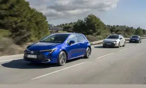 Niebieska Toyota Corolla hatchback, model hybrydowy, jedzie po krętej drodze wśród zielonych wzgórz.