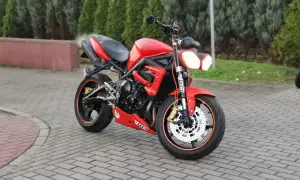 Czerwony motocykl Triumph Street Triple 675 na brukowanym podjeździe.