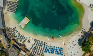 Widok z lotu ptaka na zatłoczoną plażę z leżakami i parasolami. Woda jest krystalicznie czysta. Czy Albania jest bezpiecznie? Tak, wygląda na to, że turyści cieszą się wakacjami.