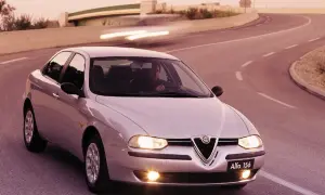 En silverfärgad Alfa Romeo 156 kör på en kurvig väg i solnedgången.