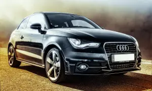Czarny Audi A1 z felgami, którego cięgno jest widoczne na drodze.