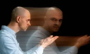 Uomo calvo con effetto mosso, sembra diviso tra due stati, un'immagine che evoca un disturbo del controllo.