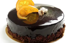 Torta lucida al cioccolato con fette d'arancia candita e nocciole. Un delizioso mousse cioccolato e arancia che invita a un assaggio.