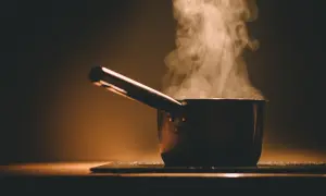 Garnek z gotującą się kaszą jaglaną i unoszącą się parą.