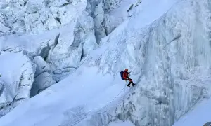 Bergsteiger seilt sich im Khumbu Icefall ab, umgeben von zerklüftetem Eis und tiefen Gletscherspalten.