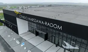 Nowoczesny budynek lotniska Warszawa-Radom z napisem "ODLOTY" i symbolem samolotu na szkle.