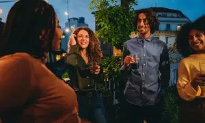 Vänner samlas på en takfest i Berlin, med ljusslingor och stadens silhuett i bakgrunden. En kväll fylld av skratt och goda drinkar, som en liten bit av fakta om Berlin.