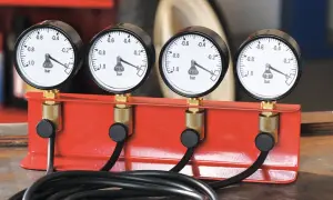 Zestaw czterech manometrów synchronizacyjnych do motocykla na czerwonej podstawie.