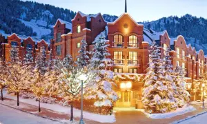 Luxuriöses Hotel im teuersten Skigebiet der Welt, umgeben von verschneiten Bäumen mit Lichterketten und Bergen im Hintergrund.