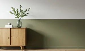 Ein Flur zweifarbig gestrichen: oben weiß, unten ein warmes Olivgrün. Ein Holzschrank mit Deko und Pflanzen.