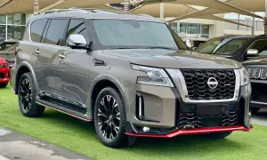Szary Nissan Patrol 2025 Nismo z czerwonymi akcentami, prezentujący się na zielonej trawie.