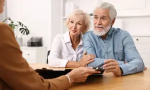 Un couple âgé discute d'une procuration pour leur compte bancaire avec un conseiller.