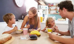 Famiglia felice a colazione, un momento sereno che fa pensare alle detrazioni figli a carico.