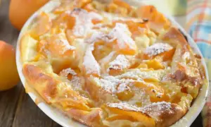 Un clafoutis moelleux aux abricots, doré et saupoudré de sucre glace, sort du four. Un délice fruité !