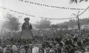 Una figura alta, vestida con traje tradicional, se alza sobre una multitud. Es parte de la **historia del Rocío**, una tradición ancestral.