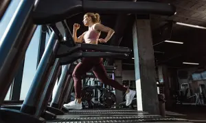 Mujer corriendo en una cinta de correr en un gimnasio moderno.
