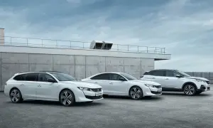 Trzy białe samochody Peugeot 508: kombi, sedan i SUV, stoją przed betonowym budynkiem.