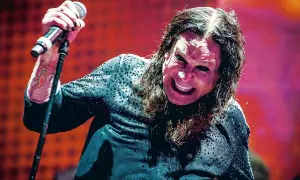 Ozzy Osbourne, wokalista Black Sabbath, z mikrofonem w dłoni, z charakterystycznym wyrazem twarzy na koncercie.