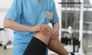 Fizjoterapeuta bada kolano pacjenta w gabinecie rehabilitacyjnym.