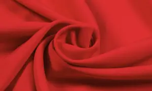 Roter Stoff, der sich zu einer Spirale drapiert. Die Textur ist glatt, was auf Lyocell oder Viskose hindeutet. Der Unterschied zwischen Lyocell und Viskose ist oft subtil.