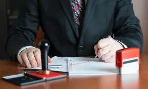 Notaio firma documenti, con timbro e inchiostro pronti per il deposito prezzo.