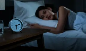 A woman lies awake in bed, staring at the clock. She's trying to figure out how to fall back asleep.