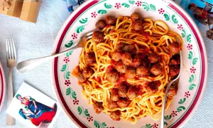 Spaghetti alla chitarra con polpettine in un piatto decorato, pronti per essere gustati.