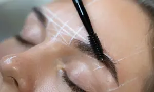 Zbliżenie na brwi z zaznaczonymi liniami i szczoteczką do ich modelowania.