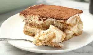Pyszne tiramisu bez jajek na talerzu, z widocznym kawałkiem na łyżeczce.