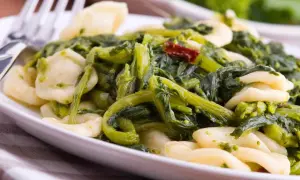 Piatto di orecchiette cime di rapa, un classico della cucina pugliese, con verdure verdi e un tocco di peperoncino.