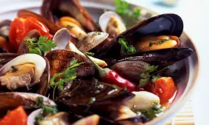 Un invitante sugo cozze e vongole, con pomodorini, peperoncino e prezzemolo fresco, pronto per essere gustato.