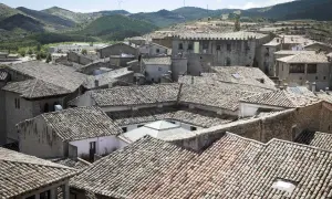 Tejado de un pueblo con colinas al fondo. Se vislumbran las torres del puente de San Valero.