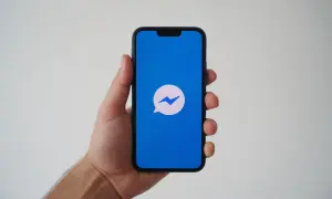 Dłoń trzyma smartfon z niebieskim ekranem i ikoną Messengera. Zastanawiasz się, dlaczego nie widzę aktywności na Messengerze?