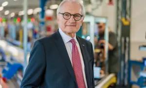 Gerteric Lindquist, en äldre man med glasögon och slips, står i en fabriksmiljö.