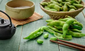 Zielone strąki edamame, miseczka z napojem i czajniczek. Czy wiesz, edamame co to?