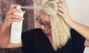 Kvinna med blont hår sliter torrschampo i håret för volym och textur.