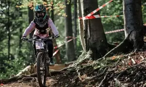 Rowerzystka w kasku z numerem 41 zjeżdża po leśnej ścieżce. To świetne **trasy rowerowe Śląsk** dla miłośników adrenaliny.