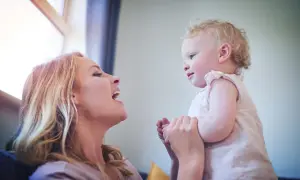 Radosna mama patrzy na swoje dziecko, które właśnie zaczyna mówić "mama".