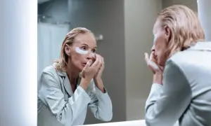 Femme appliquant des patchs sous les yeux, découvrant les matrixyl bienfaits pour une peau rajeunie.