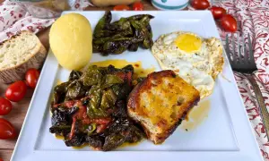 Piatto con friggitelli in padella, uovo fritto, patata lessa, pane tostato e pomodorini.