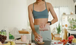 Frau bereitet einen protein shake abnehmen zu. Gesunde Zutaten wie Obst und Gemüse sind auf dem Tisch.